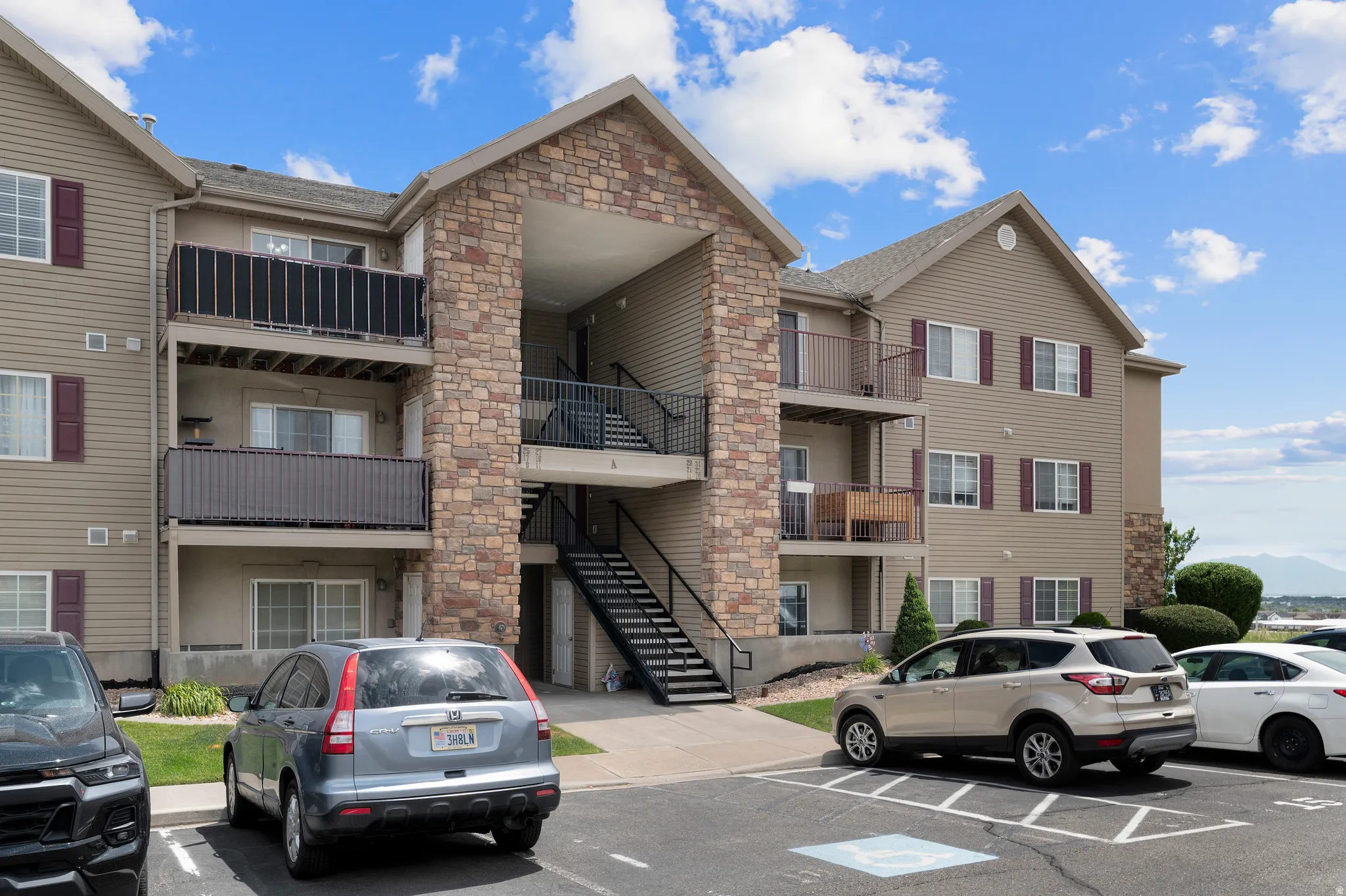 Multi-story residential building featuring a stone facade and beige siding
