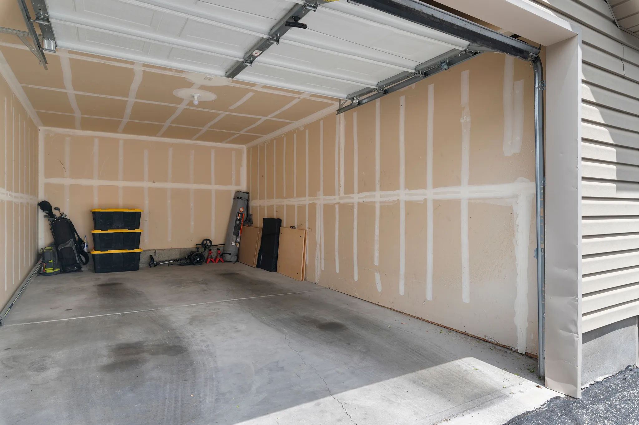 Interior garage featuring an open overhead door, concrete flooring, and unfinished walls