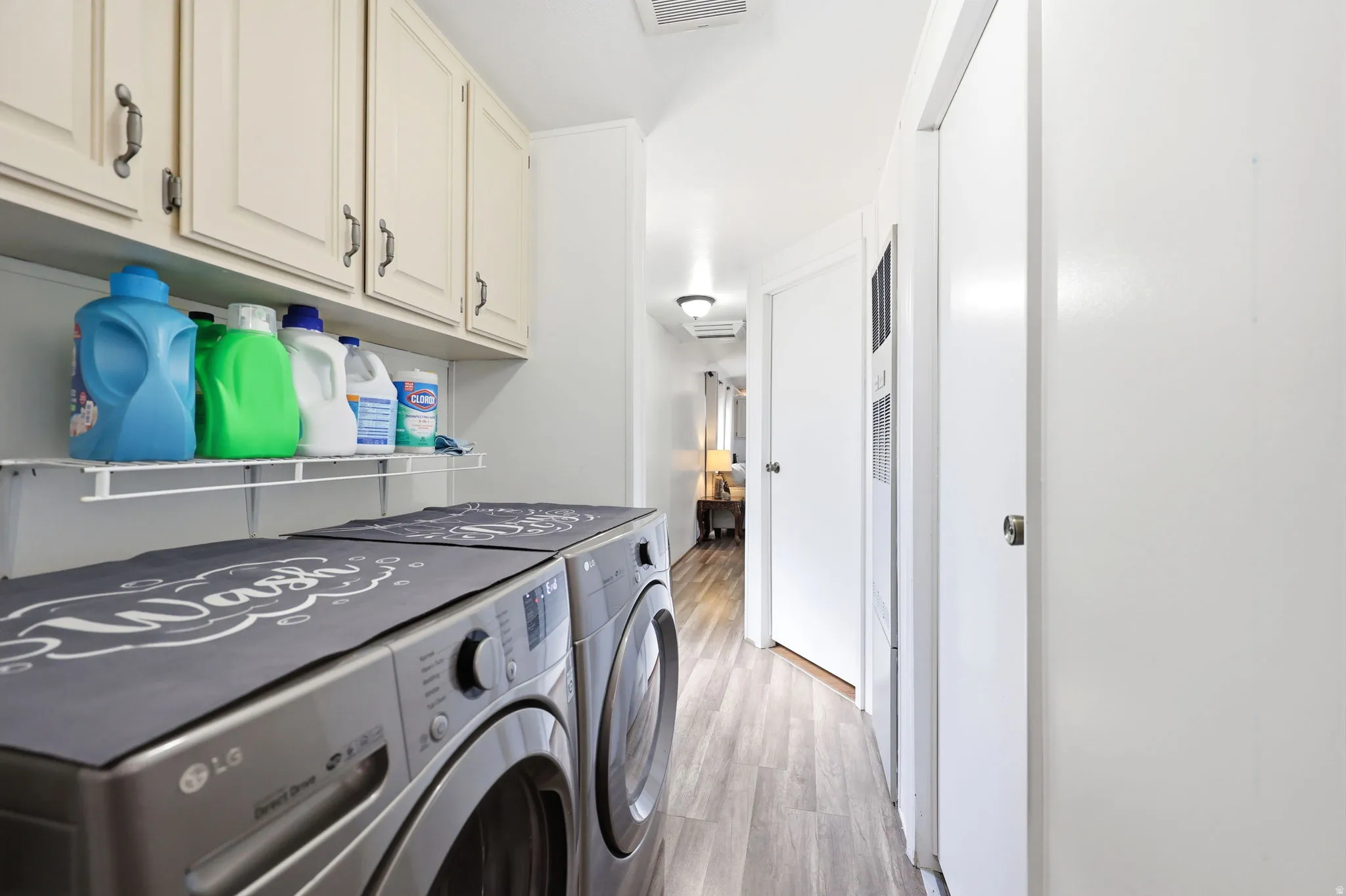 Dedicated laundry area featuring overhead cabinetry, a wire storage shelf, and wood-finish flooring