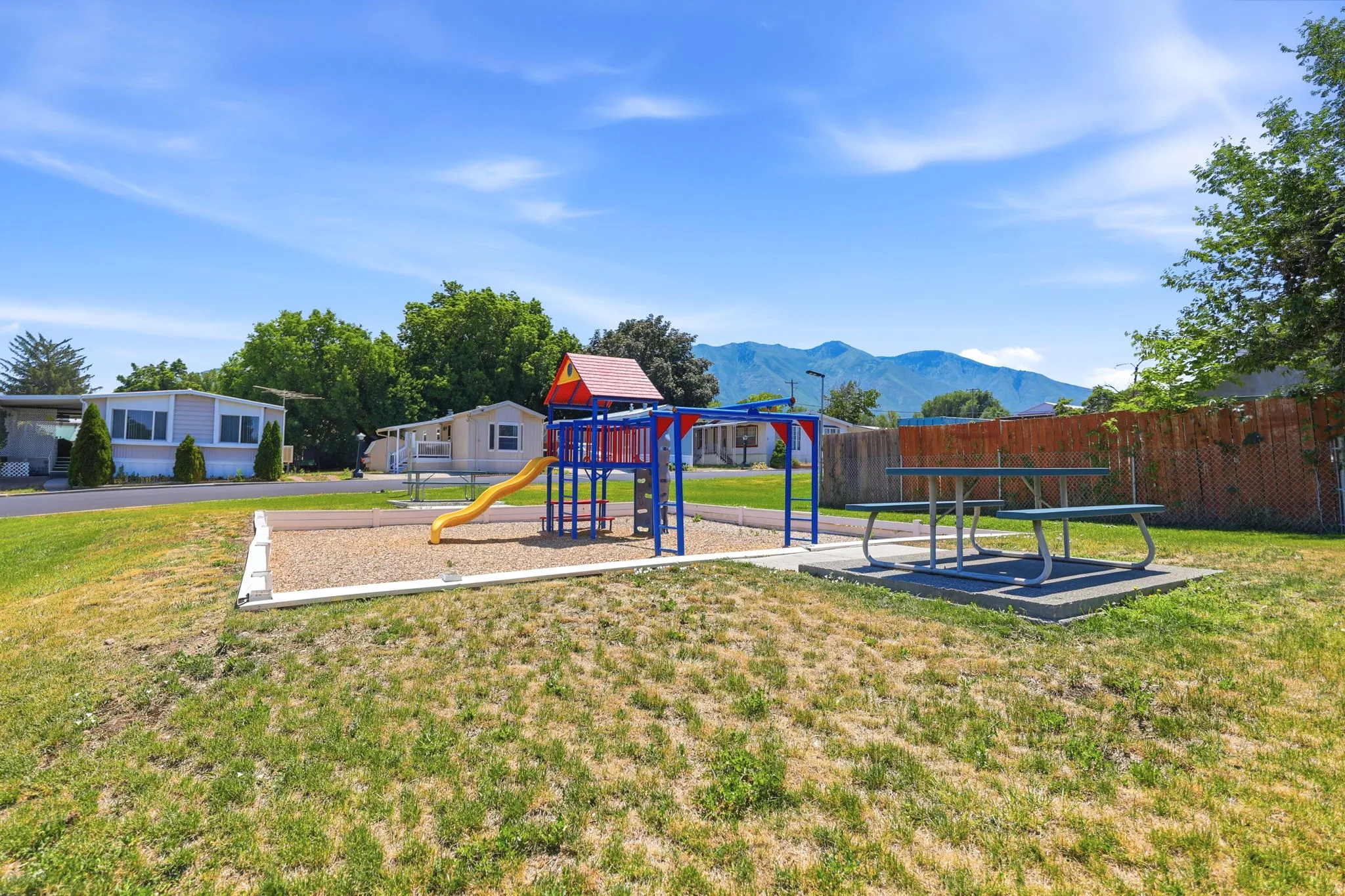 Community recreational area featuring a playground structure with a slide and a picnic table on a concrete pad