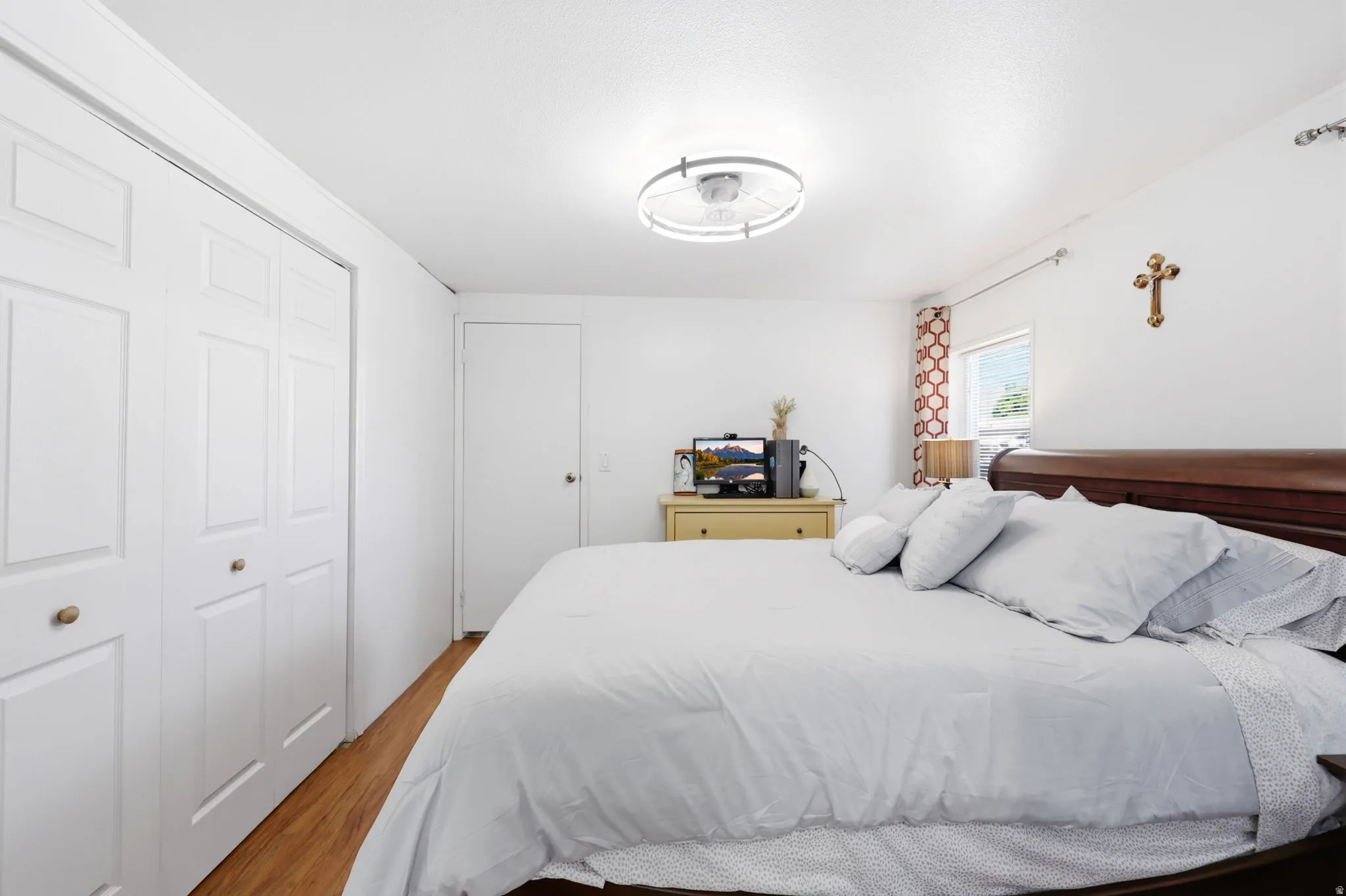 Bright interior space featuring wood-finish flooring, white walls, and a modern ceiling light fixture