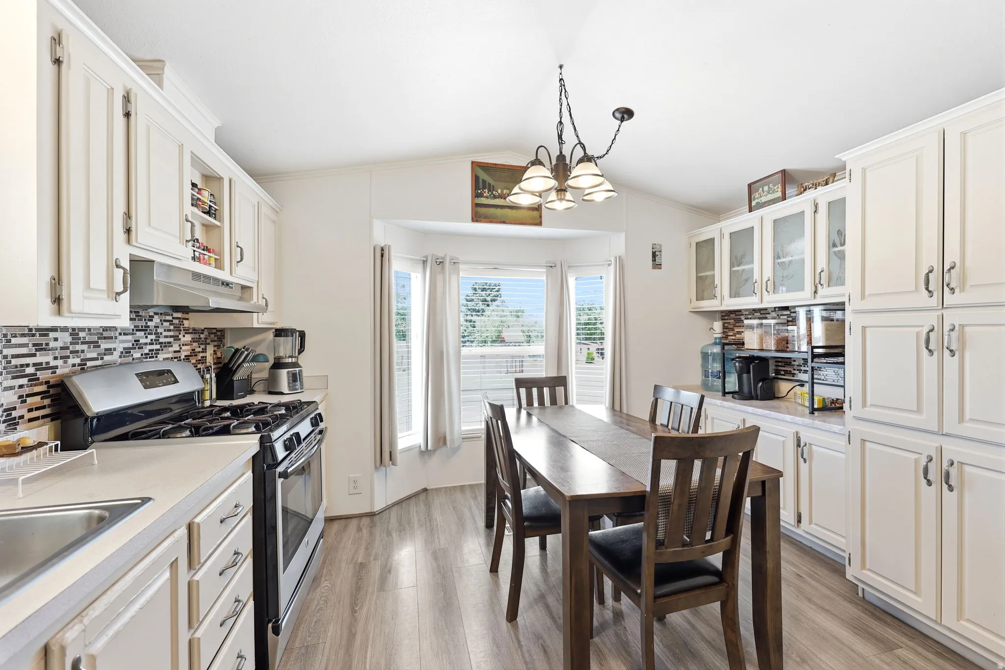 Kitchen featuring ample white cabinetry, a tiled backsplash, and wood-finish flooring