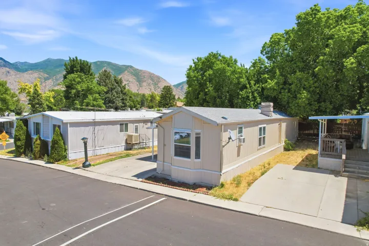 Single-story manufactured home featuring a light-colored exterior and a covered porch with railing