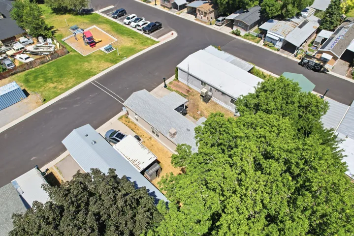 Property featuring a paved road, mature trees, and a nearby community park with play equipment