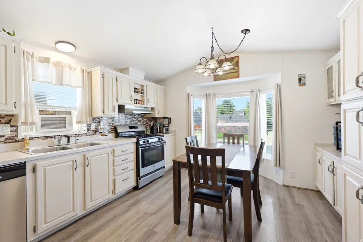 Kitchen featuring light-toned cabinetry, stainless steel appliances, and wood-finish flooring