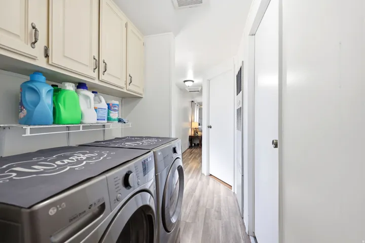 Dedicated laundry area featuring overhead cabinetry, a wire storage shelf, and wood-finish flooring