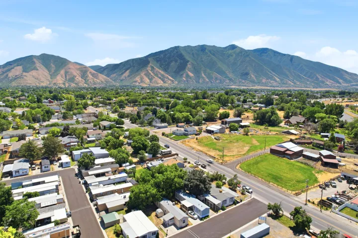 Expansive aerial landscape featuring a residential area with varied housing structures, mature trees, and mountainous terrain
