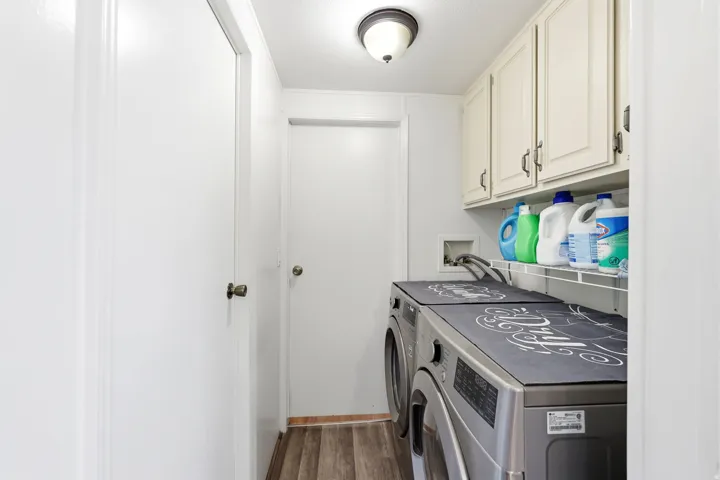 Dedicated laundry area featuring overhead cabinetry, a tiled backsplash, and wood-finish flooring