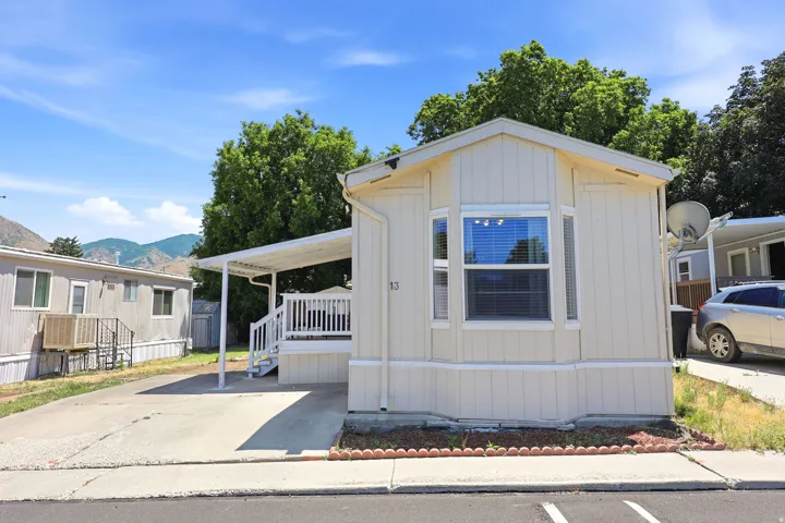 Beige siding exterior with a bay window, covered porch, and carport