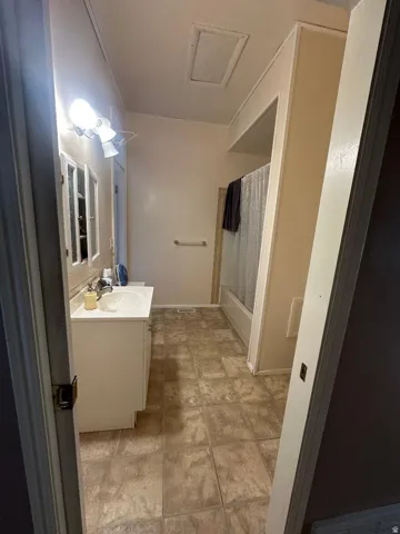Bathroom featuring a white vanity with integrated sink, tiled flooring, a built-in tub with shower, and a medicine cabinet with mirrored doors