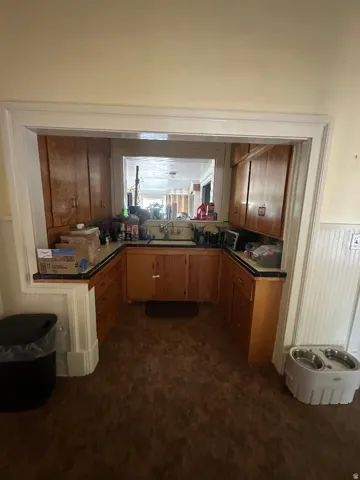 Kitchen area featuring wood cabinetry, dark countertops, and a window opening