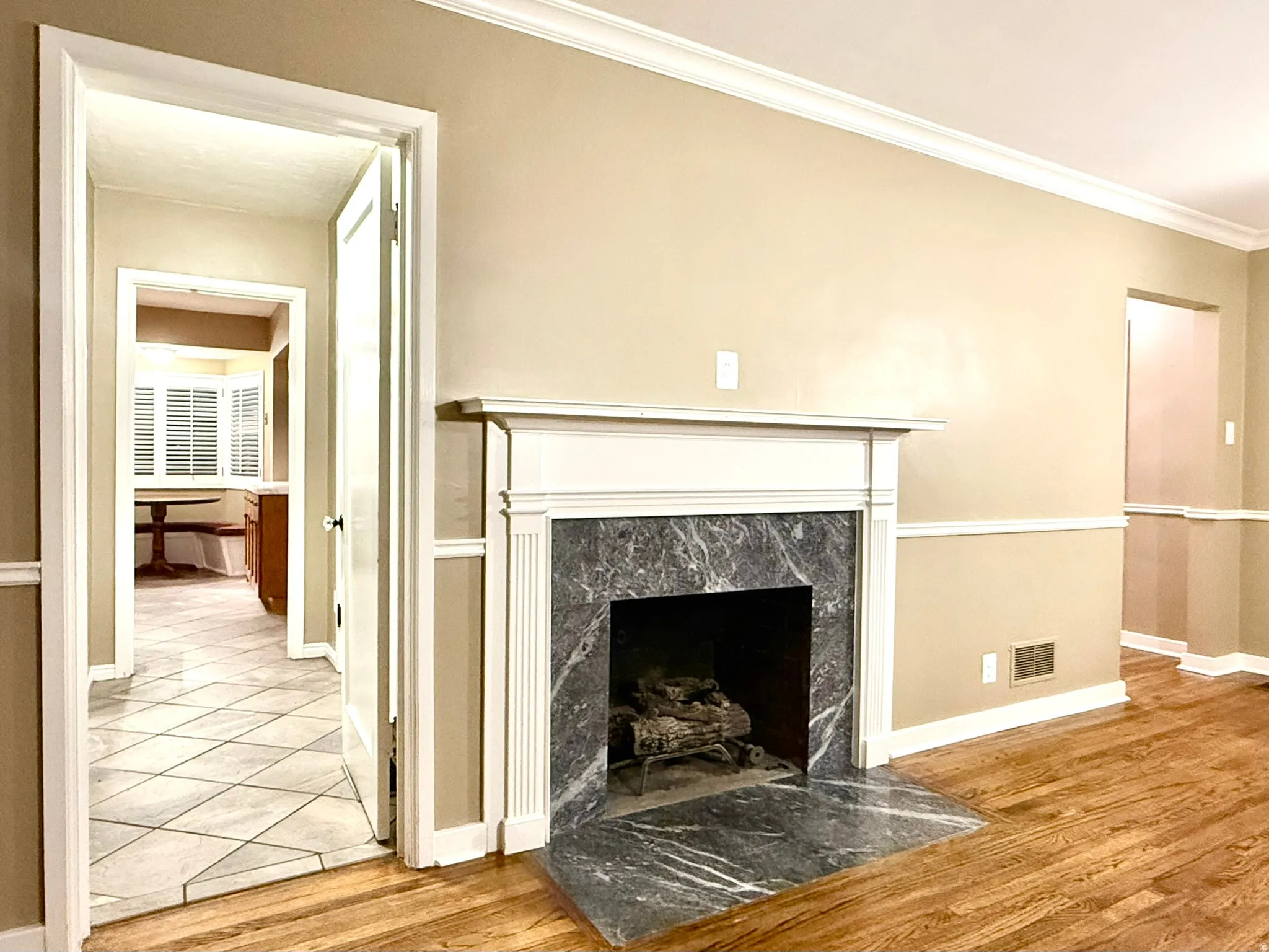 Living area featuring a classic fireplace with a stone surround and hearth, wood-finish flooring, and crown molding