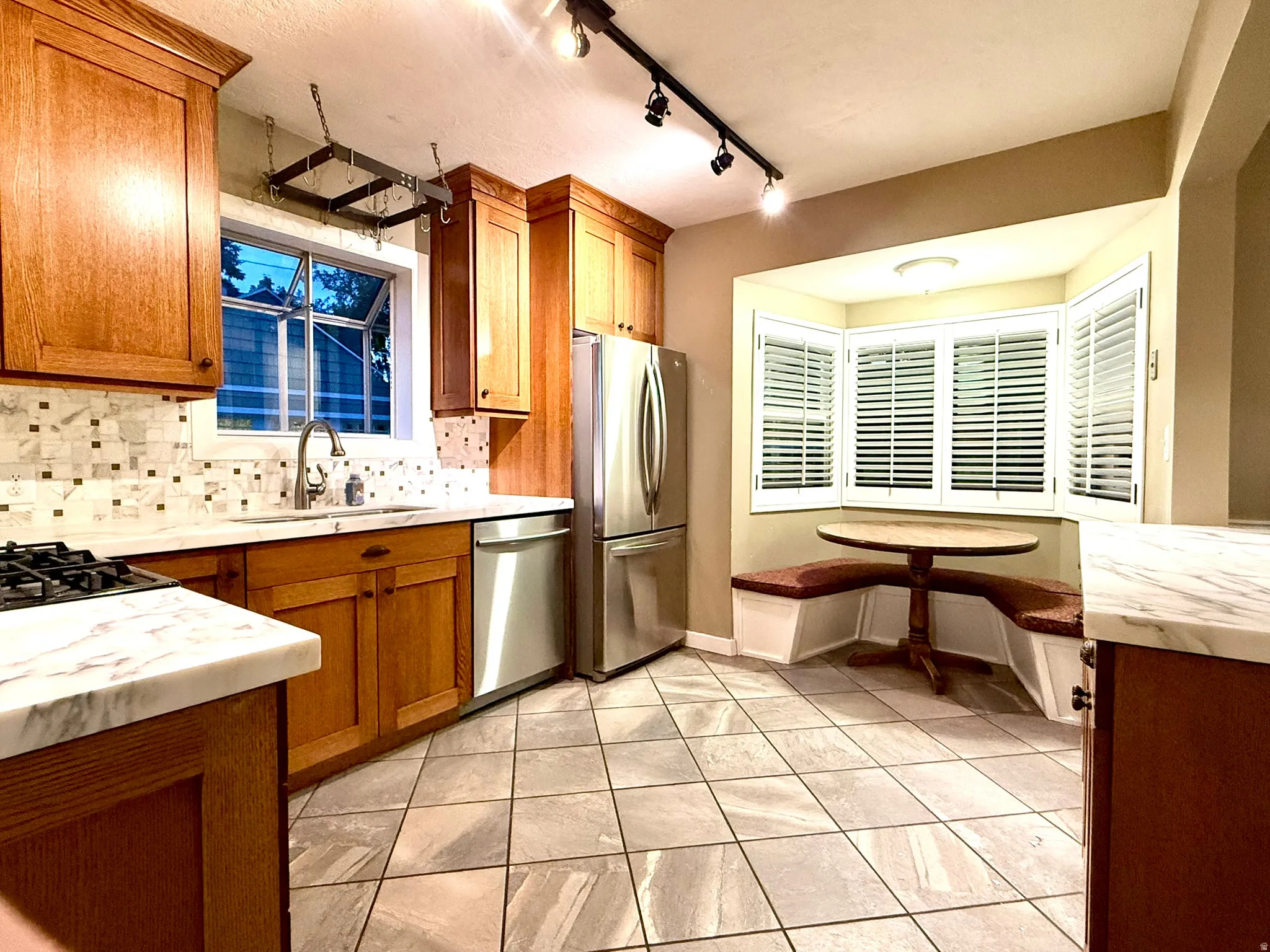 Kitchen featuring wood cabinetry, stainless steel appliances, a tile backsplash, and stone countertops