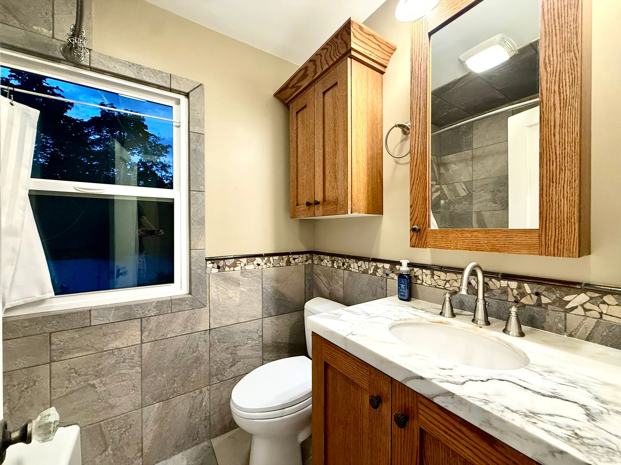 UL Bathroom featuring a marble-finish countertop vanity with an undermount sink, wood-finish cabinetry, and a framed mirror
