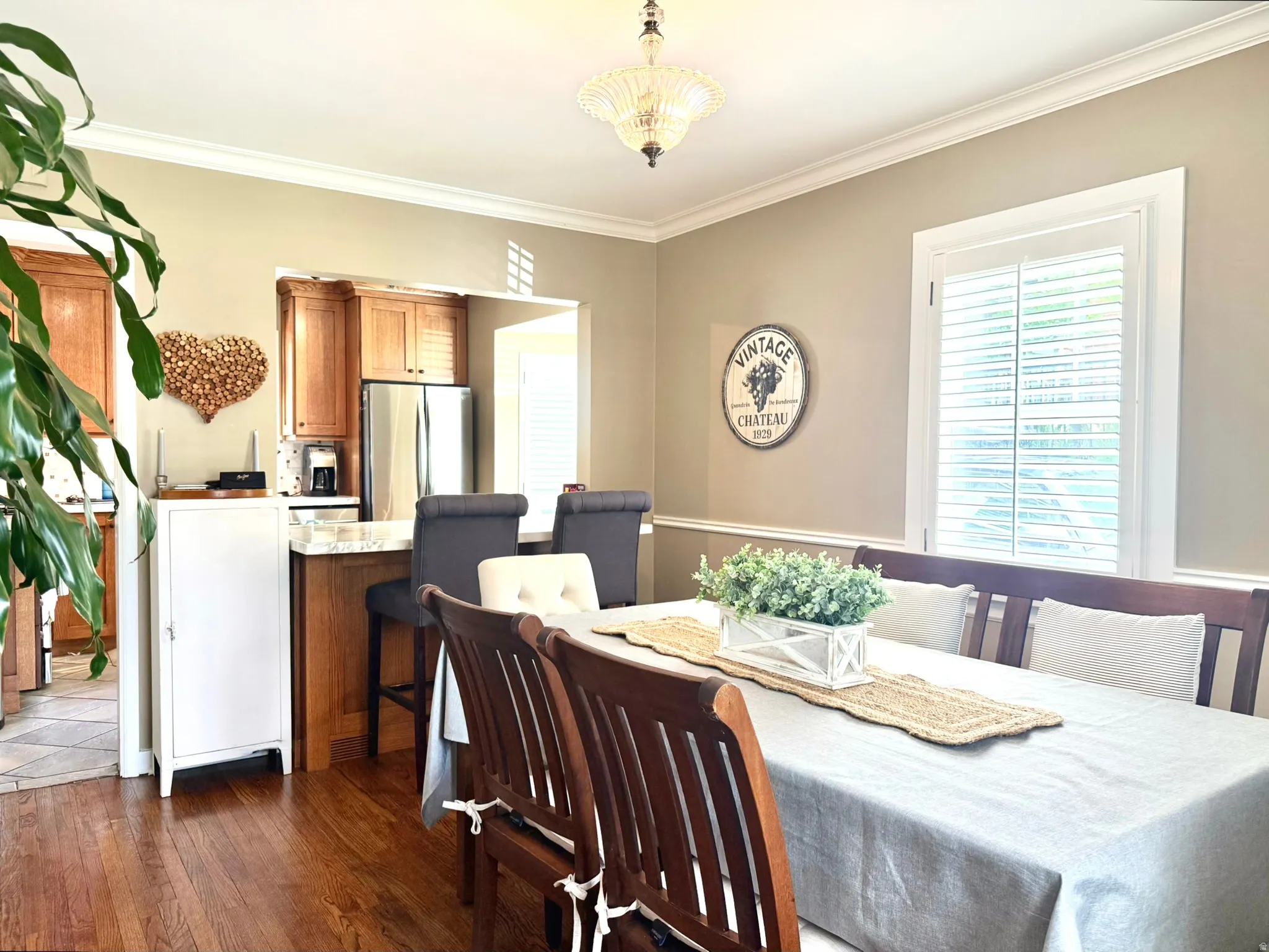 Dining area featuring wood-finish flooring, crown molding, and a chandelier