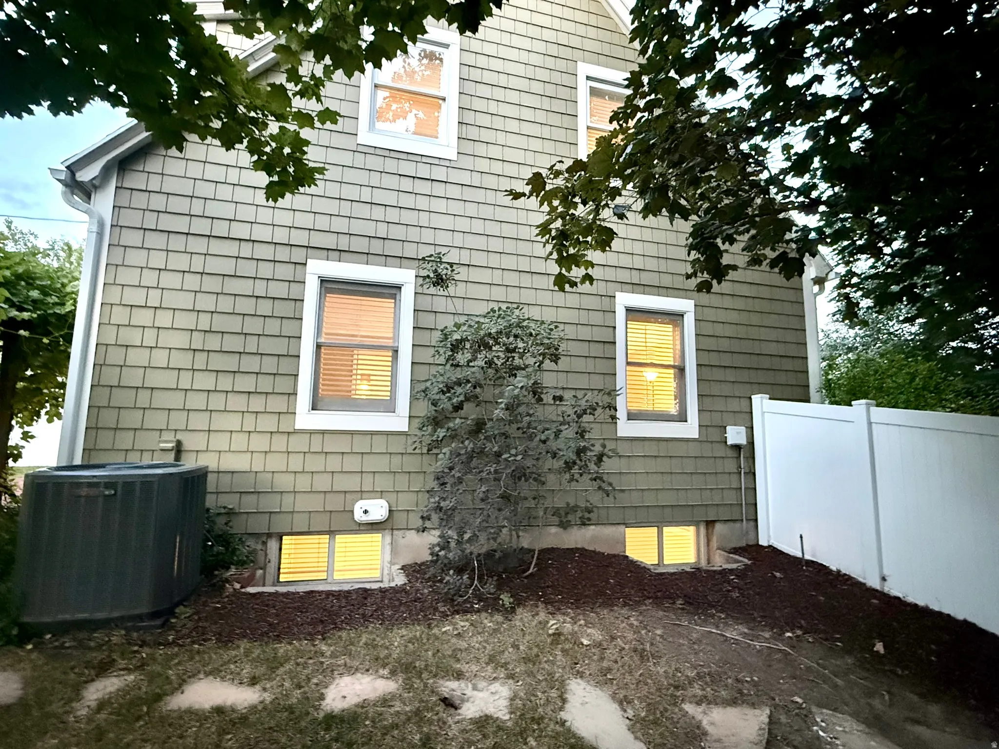 Shingle siding exterior with white trim windows and a white vinyl privacy fence