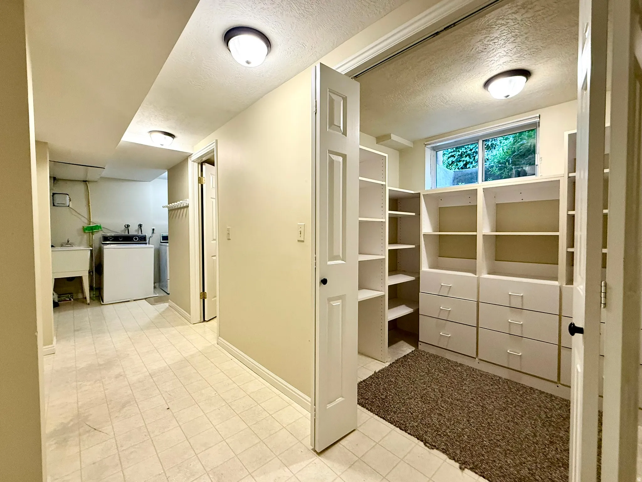 Interior utility space featuring a laundry area with a utility sink, a built-in washer and dryer, and a separate room with built-in shelving and drawers