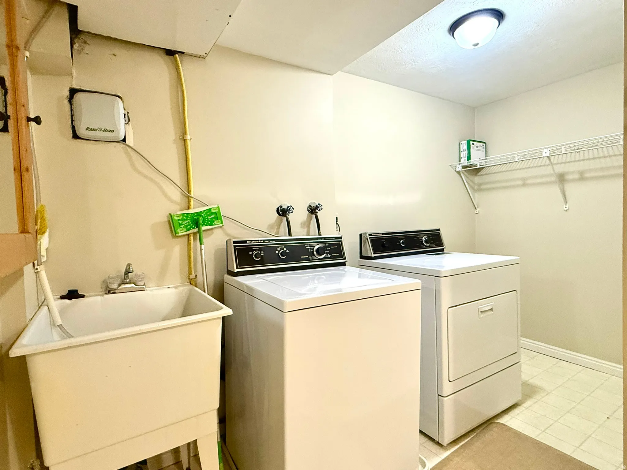 Dedicated laundry area featuring a utility sink with a chrome faucet, light-toned wall paint, and overhead lighting