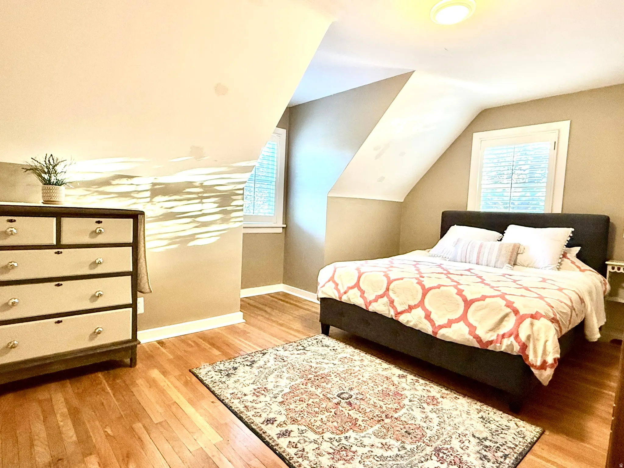 Bedroom #2  featuring wood-finish flooring, two windows, sloped ceilings, and a flush-mount ceiling light