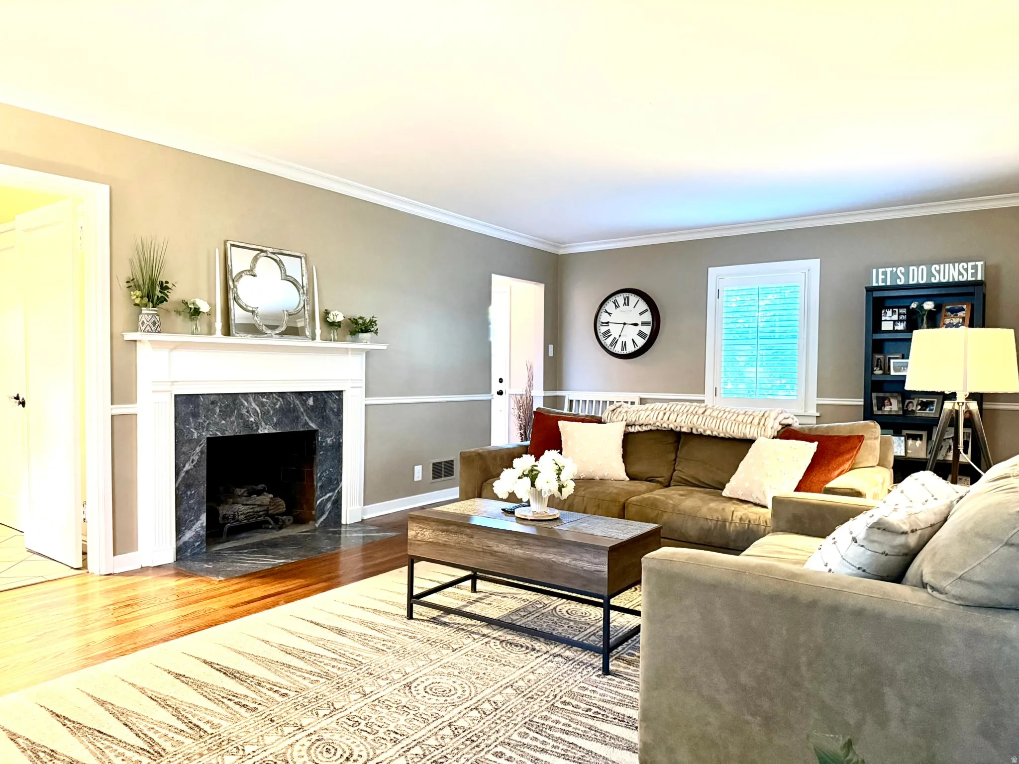 Living room featuring wood-finish flooring, a white mantel, and a dark stone fireplace surround