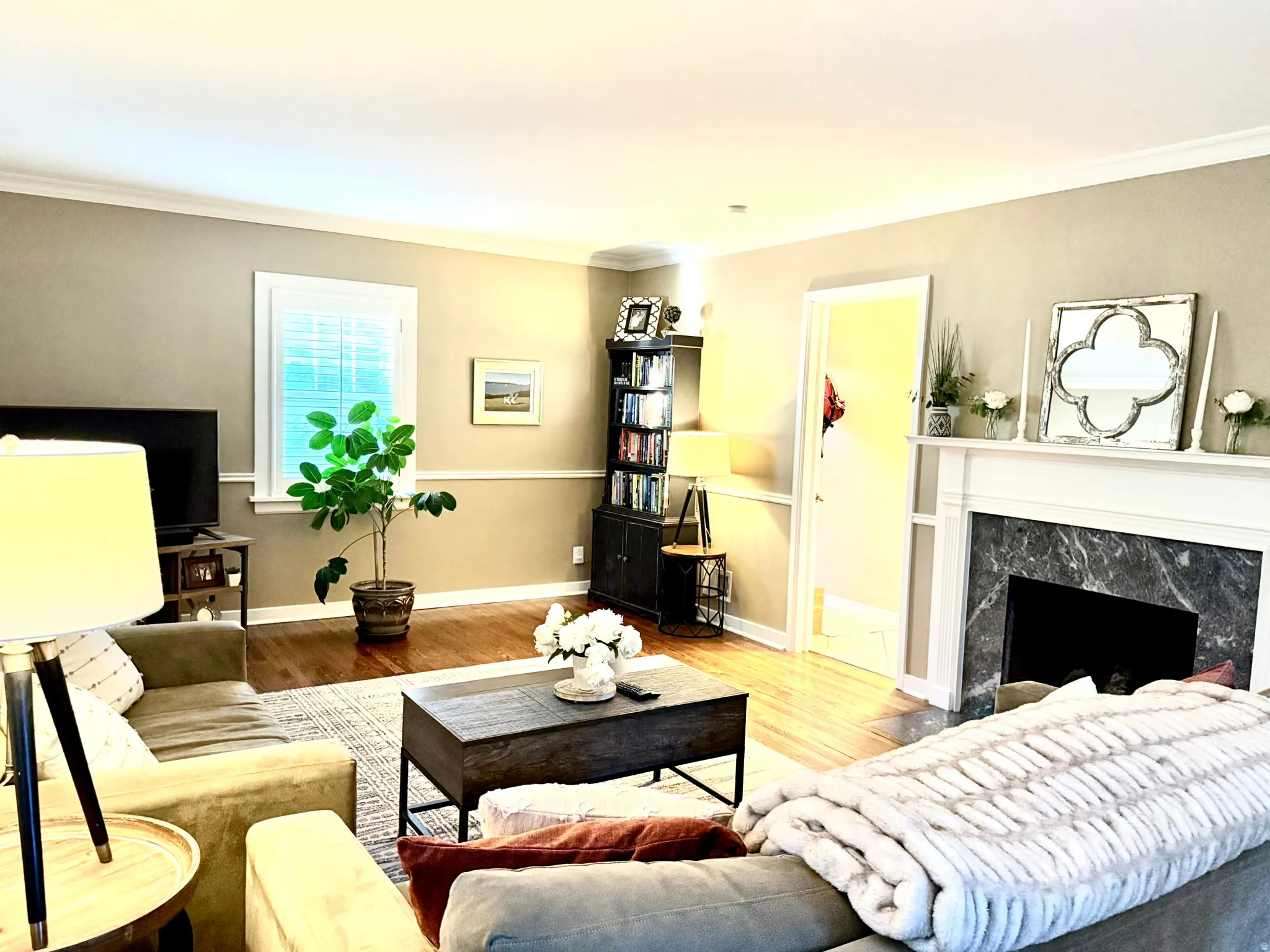 Living area with wood-finish flooring, a white-mantled fireplace, and dark-toned stone surround