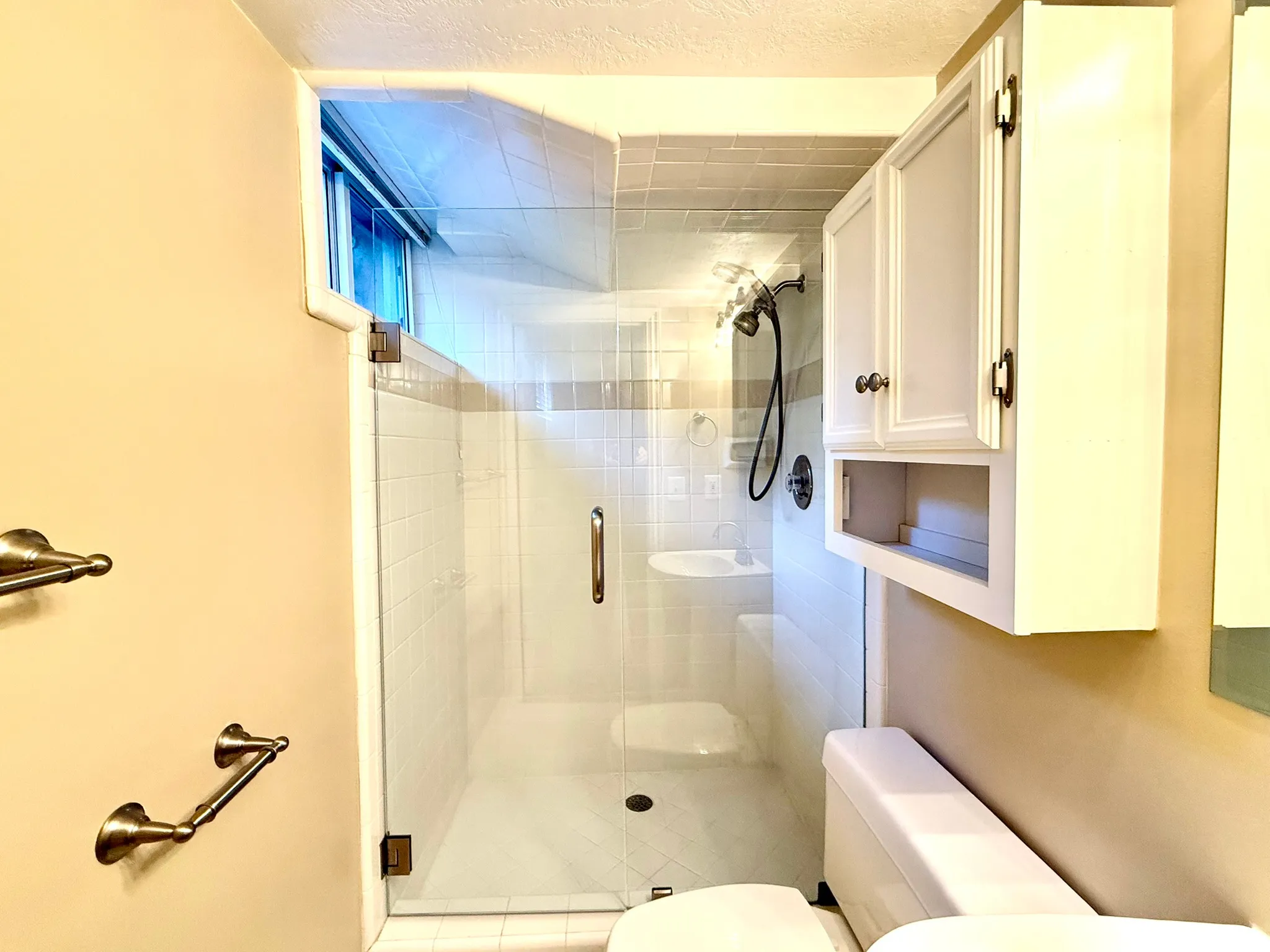 LL Bathroom Full glass shower enclosure featuring a white tile surround and integrated shelving