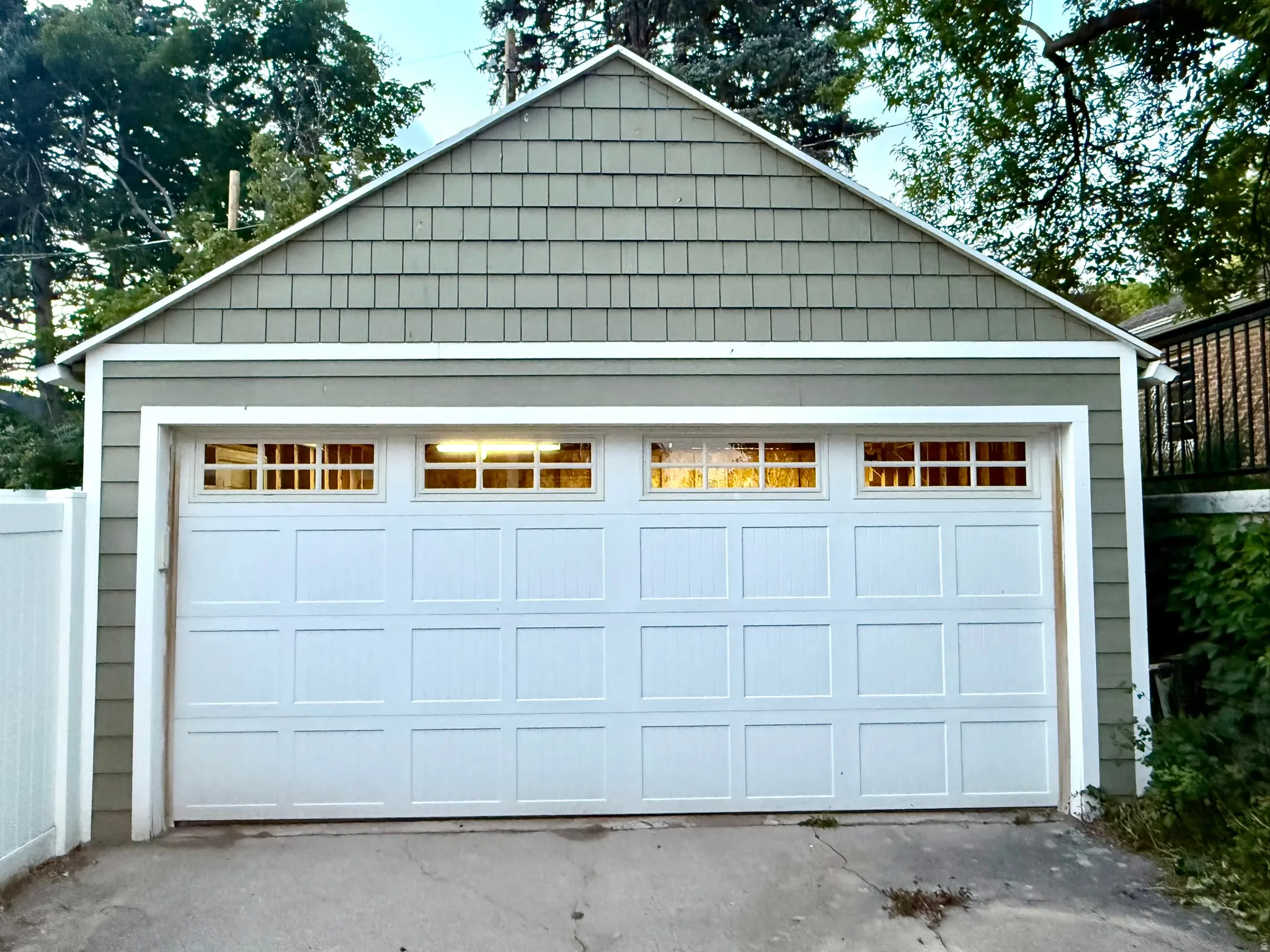 Detached garage featuring a paneled door with upper window inserts, horizontal siding, and gable-end cedar shake shingles