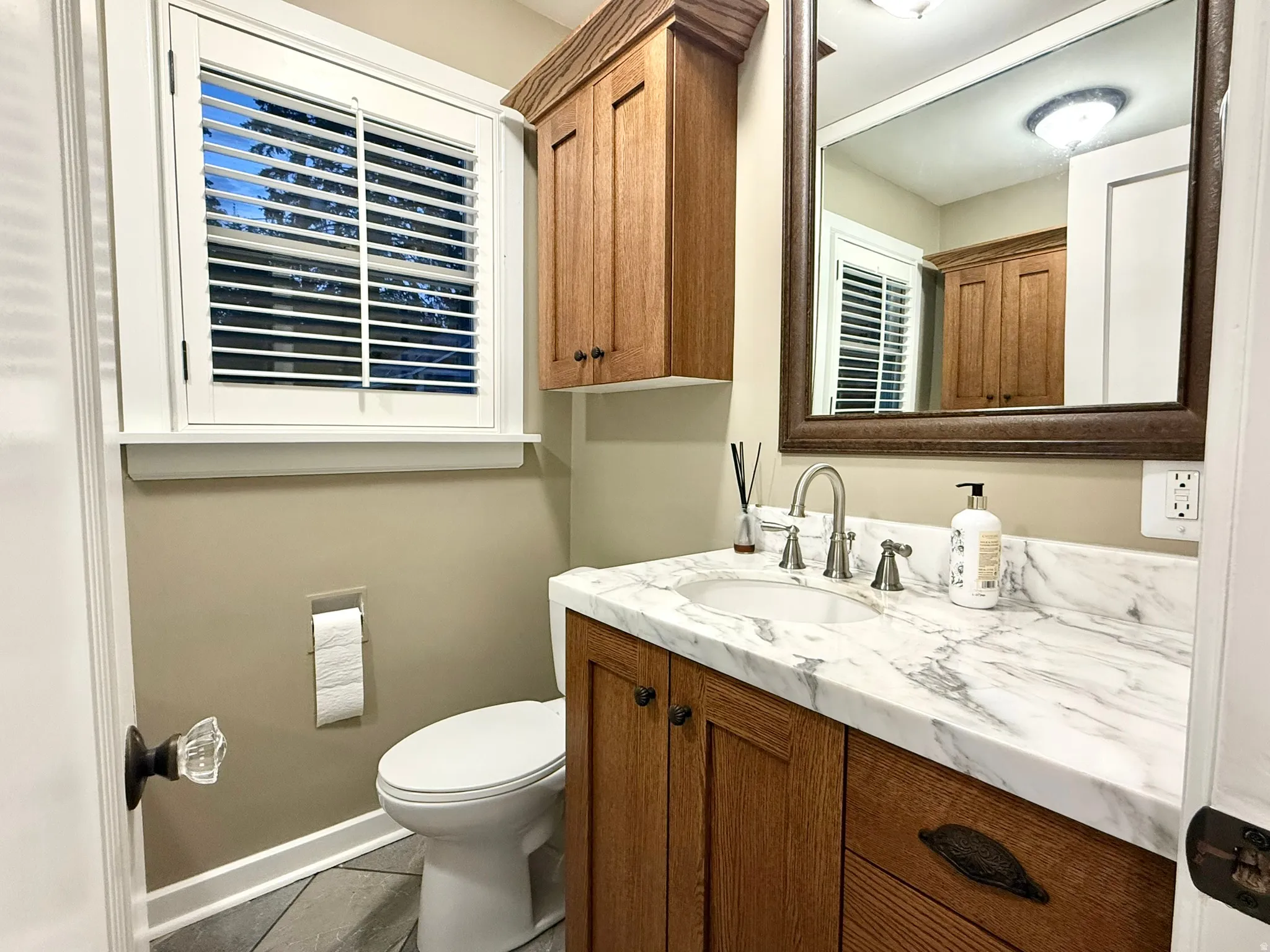 Powder Bath on Main Floor vanity with a white marble-finish countertop, undermount sink, and brushed nickel faucet