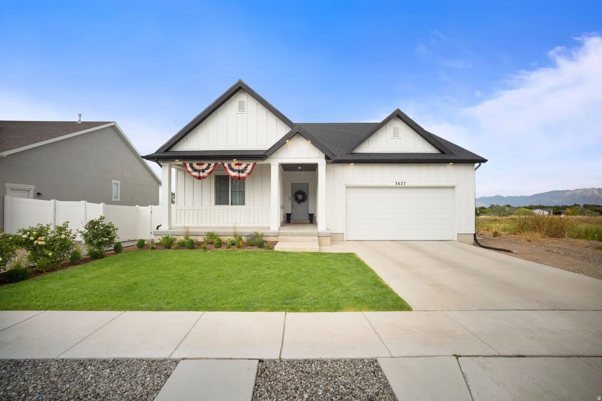 Modern farmhouse exterior featuring white vertical siding and black trim accents