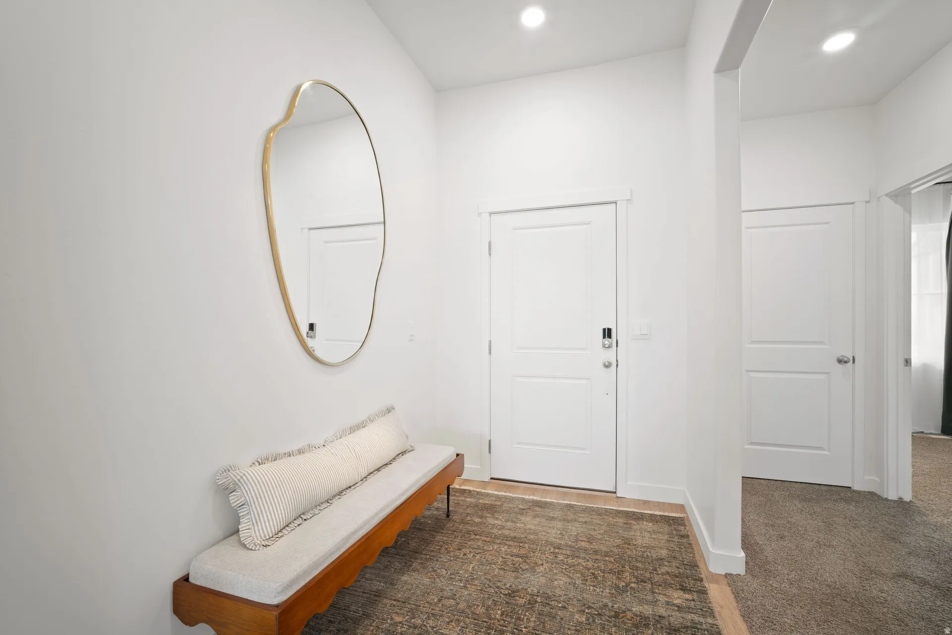 Entryway featuring a white paneled door with smart lock, recessed lighting, and a textured area rug
