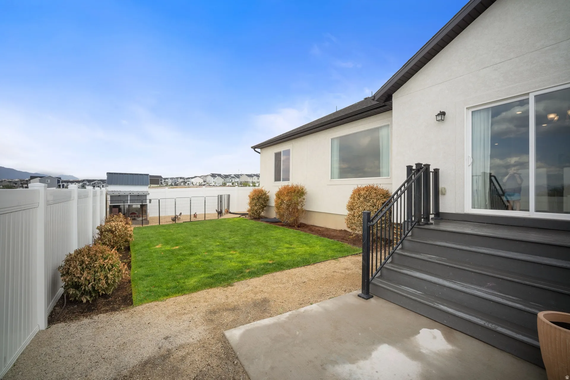 Exterior deck with dark composite steps and black metal railings, alongside a manicured lawn area