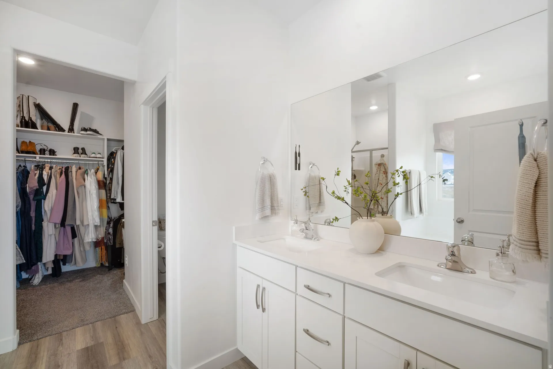 Dual vanity with white cabinetry, integrated sinks, chrome fixtures, and a large wall-mounted mirror