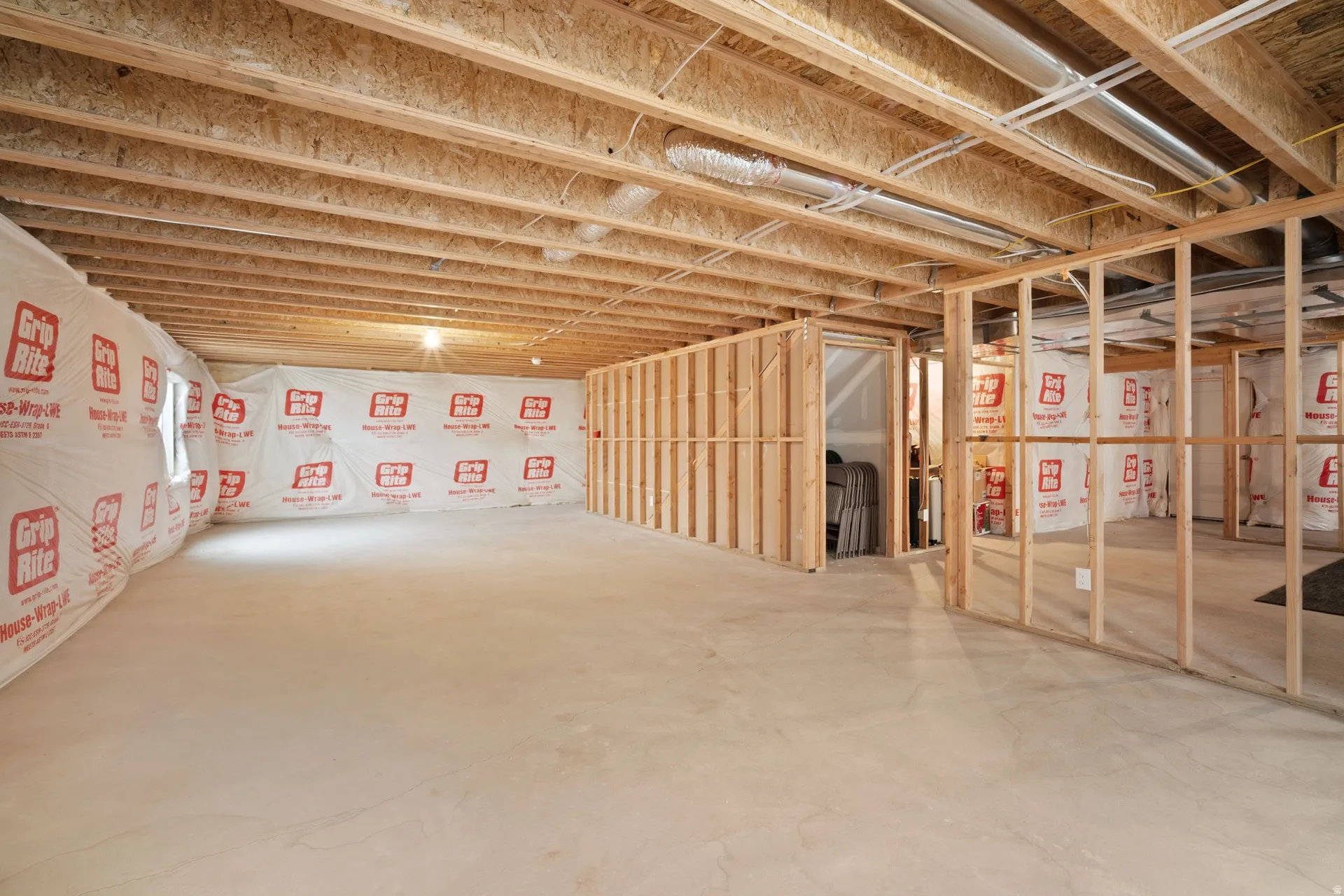 Expansive unfinished lower level featuring exposed wood joists, framed interior walls, and a concrete floor