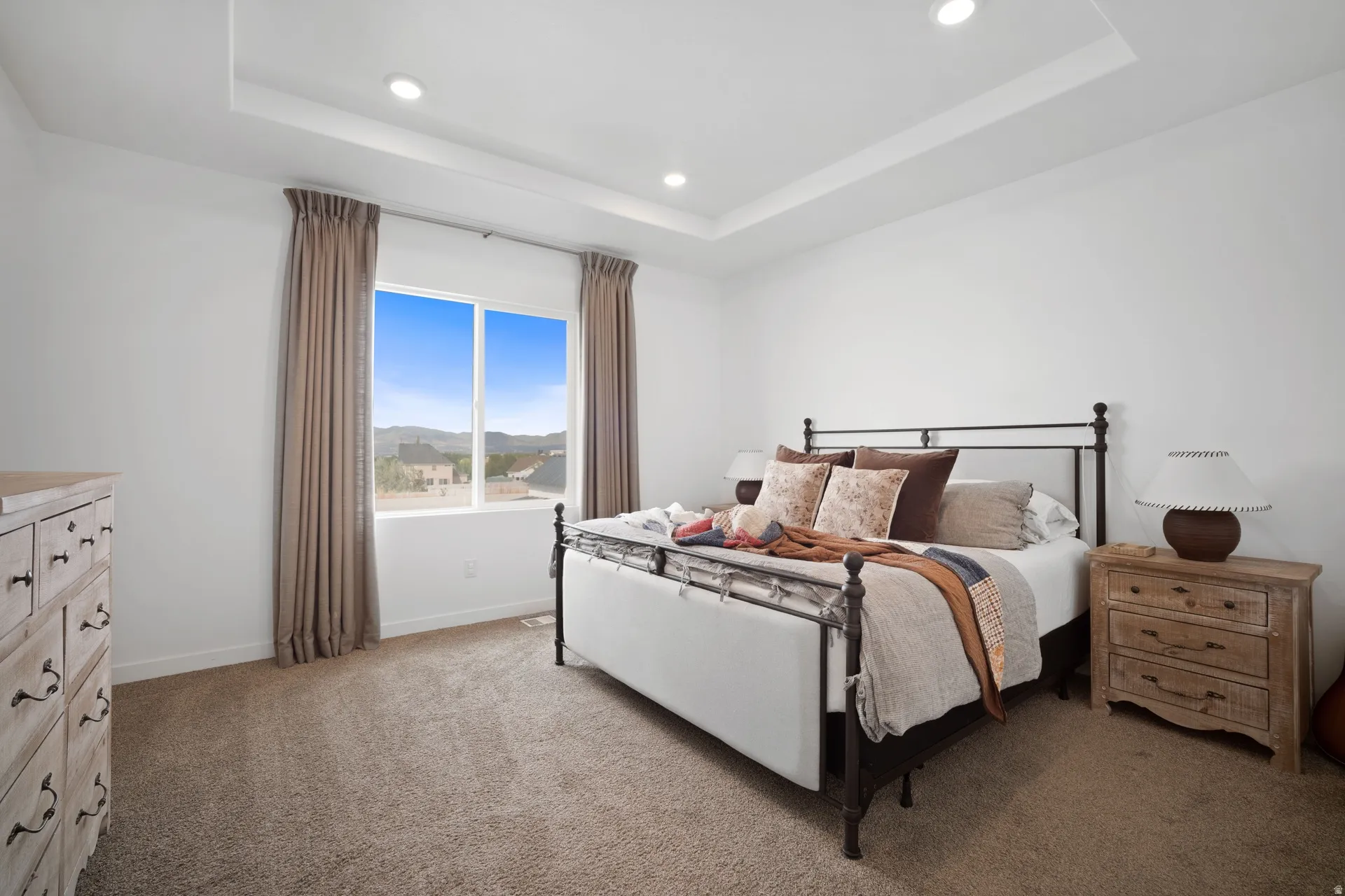 Spacious room featuring a tray ceiling with recessed lighting, carpet flooring, and a large window