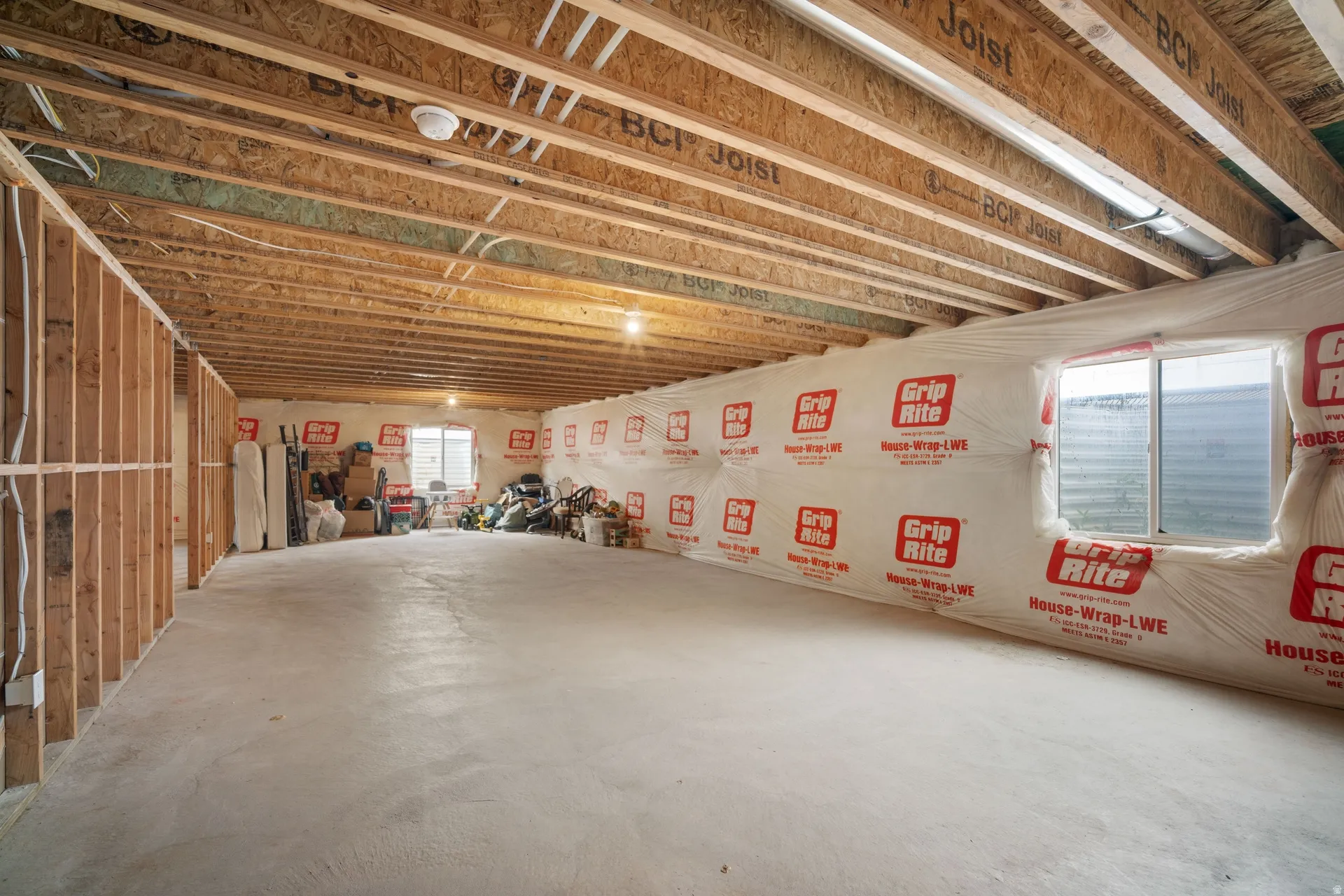 Unfinished basement offering expansive potential, featuring exposed BCI joists, framed interior walls, and two egress-style windows providing natural light