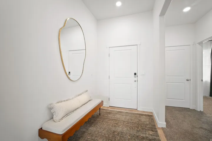 Entryway featuring a white paneled door with smart lock, recessed lighting, and a textured area rug