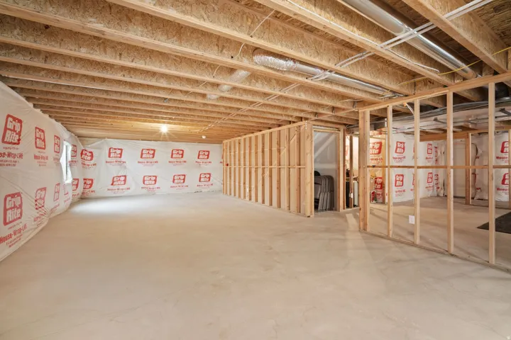 Expansive unfinished lower level featuring exposed wood joists, framed interior walls, and a concrete floor