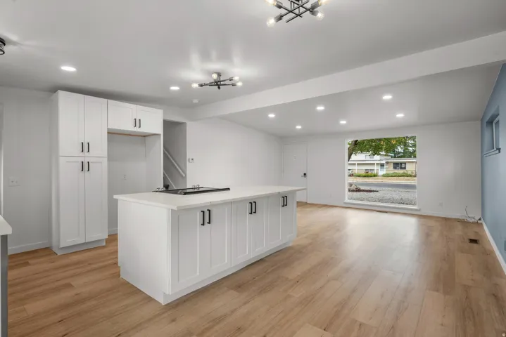 Modern kitchen island with a stone-finish countertop and built-in cooktop, complemented by white shaker-style cabinetry with matte black hardware