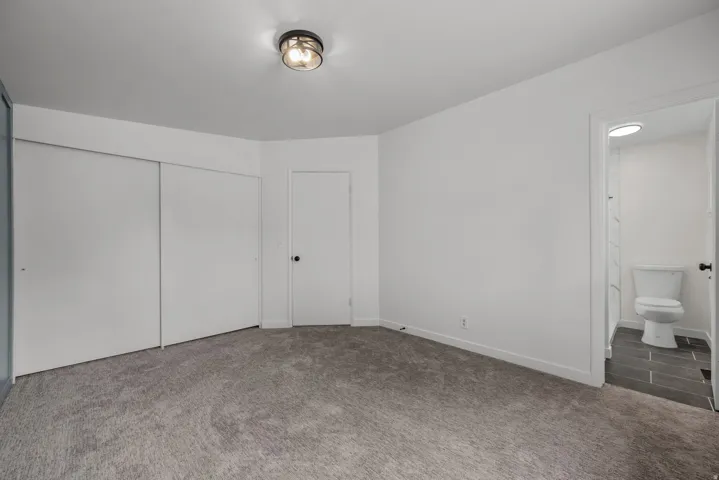Carpeted room featuring a ceiling-mounted light fixture, white walls, and white baseboards