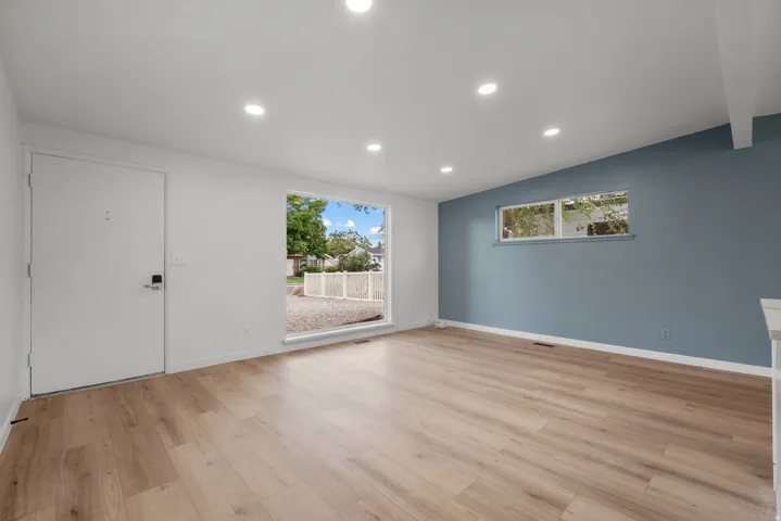 Spacious room featuring wood-finish flooring, recessed lighting, and a prominent accent wall