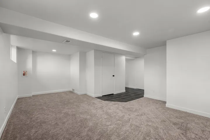 Spacious room featuring neutral carpeting, recessed lighting, white walls, and a dedicated laundry hookup area