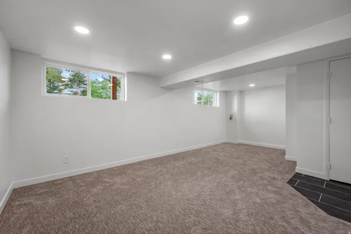 Carpeted room with recessed lighting, two windows, and white walls