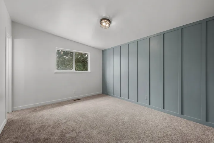Carpeted room with a feature wall showcasing vertical paneling
