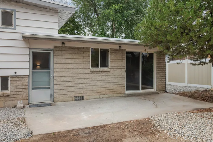 Rear exterior featuring a concrete patio, brick and siding facade, sliding glass door, and a screen door entry