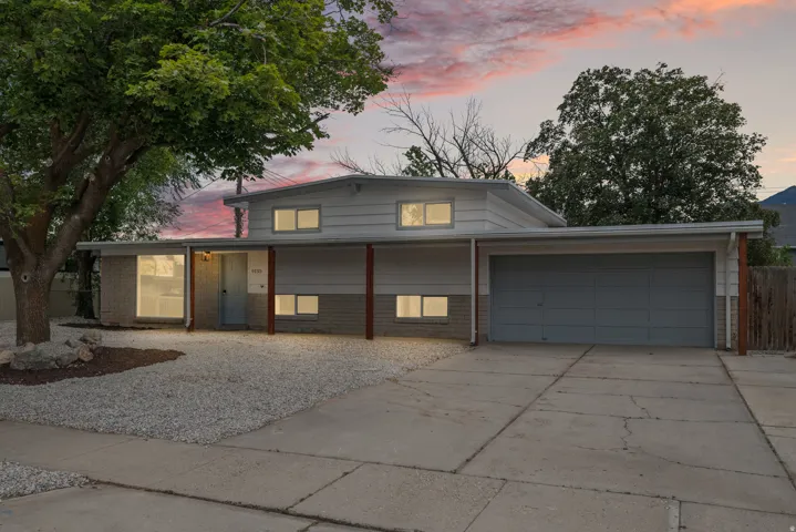 Contemporary split-level residence featuring a light gray facade with brick accents