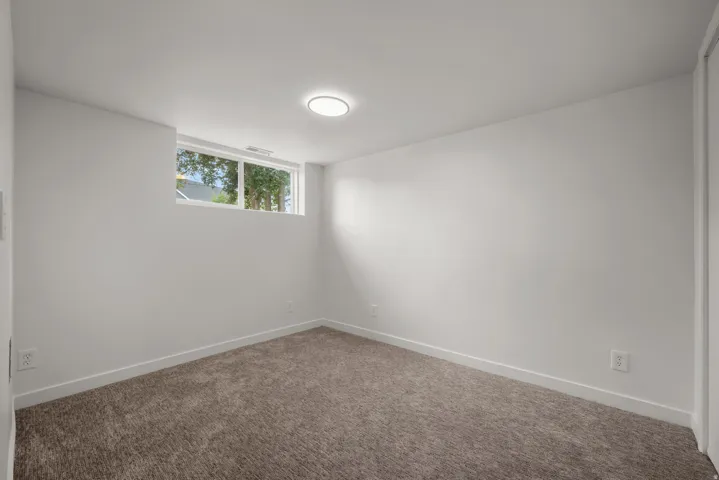 Bright room featuring plush carpet flooring, white painted walls, a white trim baseboard, and a double-pane window