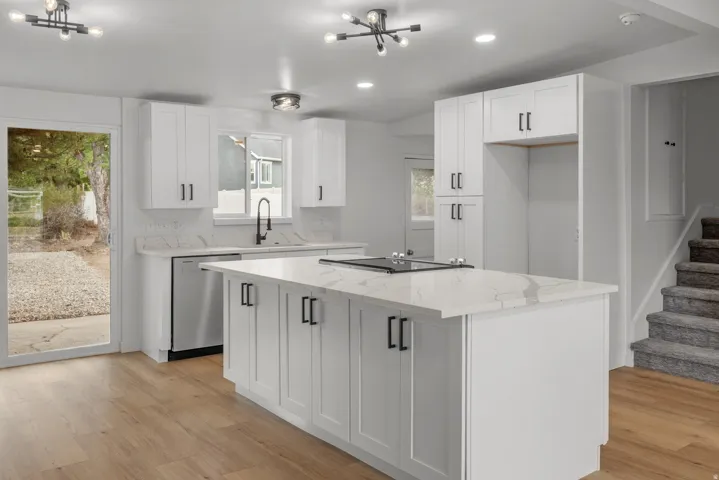 Modern kitchen featuring white shaker cabinetry, stone countertops, and wood-finish flooring