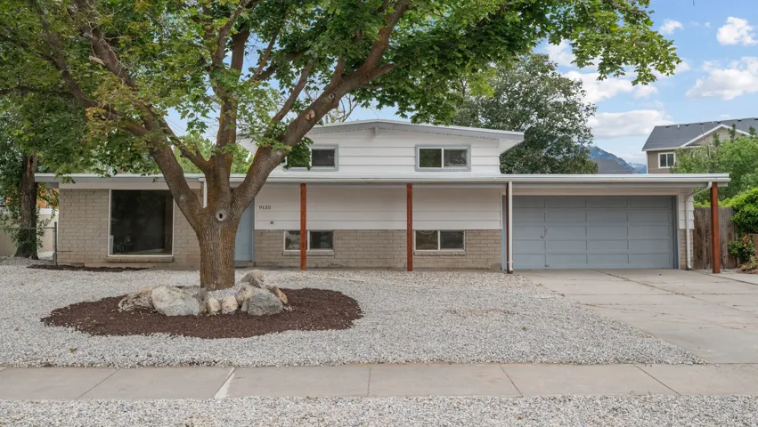 Mid-century modern exterior featuring white siding, brick accents, and a light gray garage door