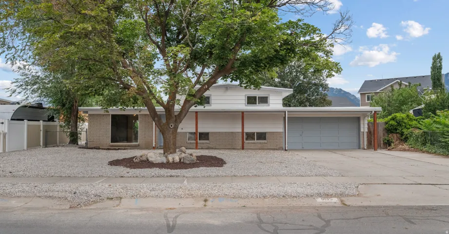 Mid-century modern exterior featuring a two-car garage, white siding, and brick accents