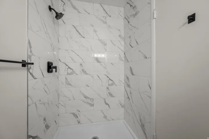 Shower with white marble-look subway tile surround, matte black shower head, and matte black single-handle shower control